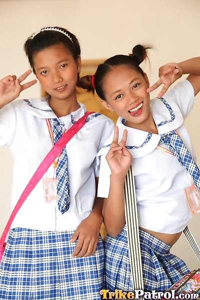 Young Asian schoolgirls lift their uniform skirts to show tiny bare pussy